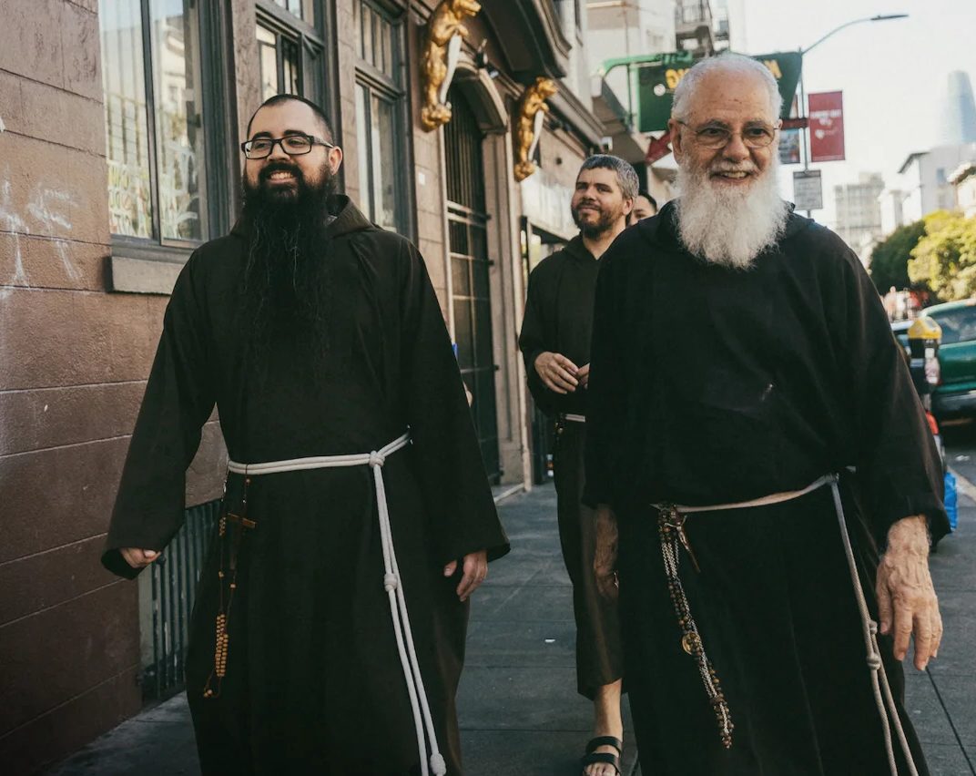 Three Capuchin friars walking down a San Francisco sidewalk